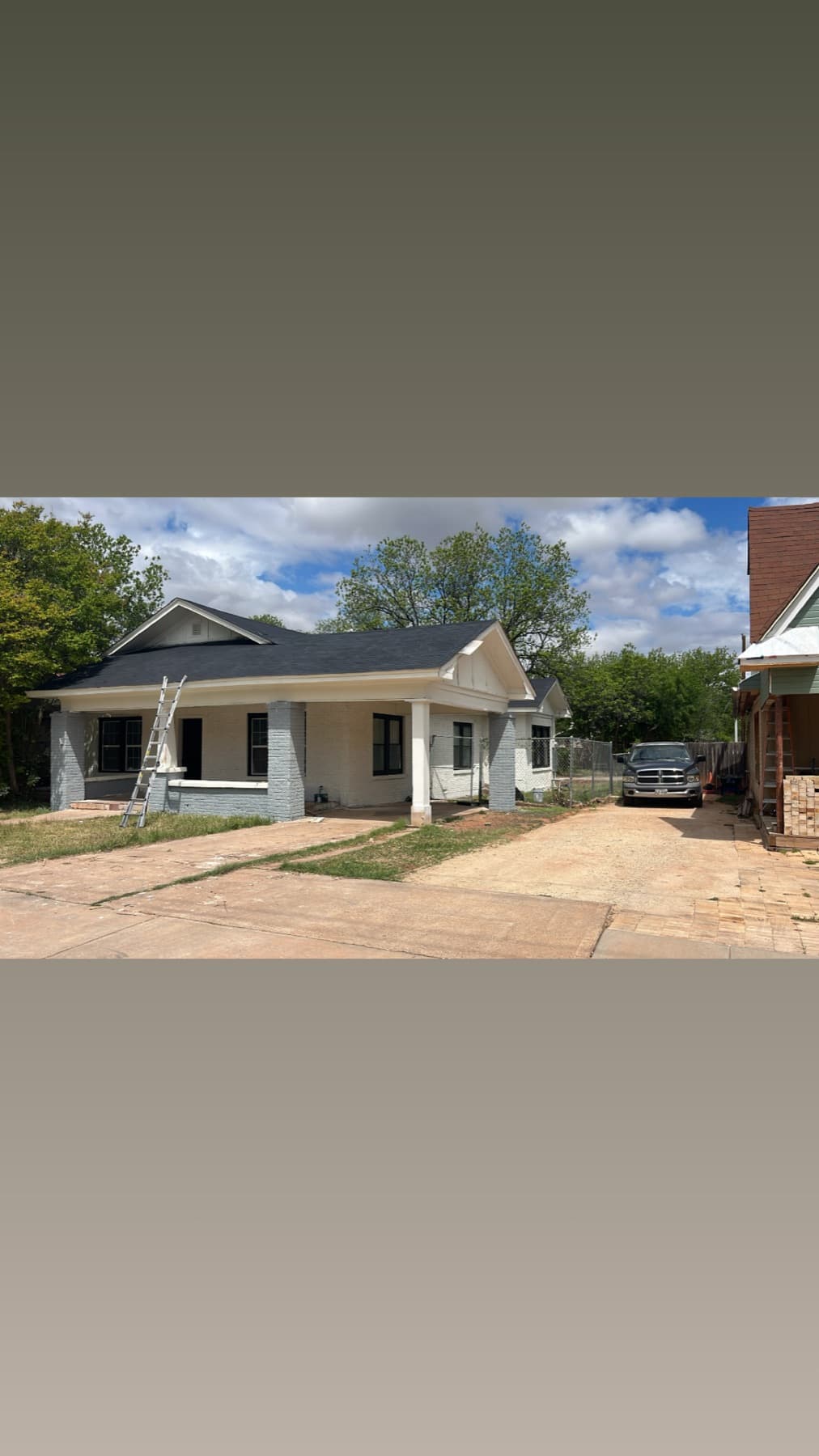 White bungalow exterior after repaint with black window trim