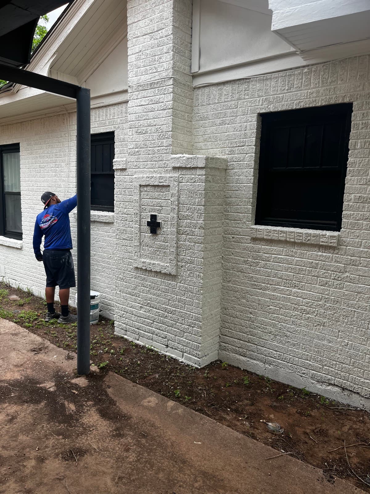 Hermanos Painting team member painting a white brick exterior with black trim